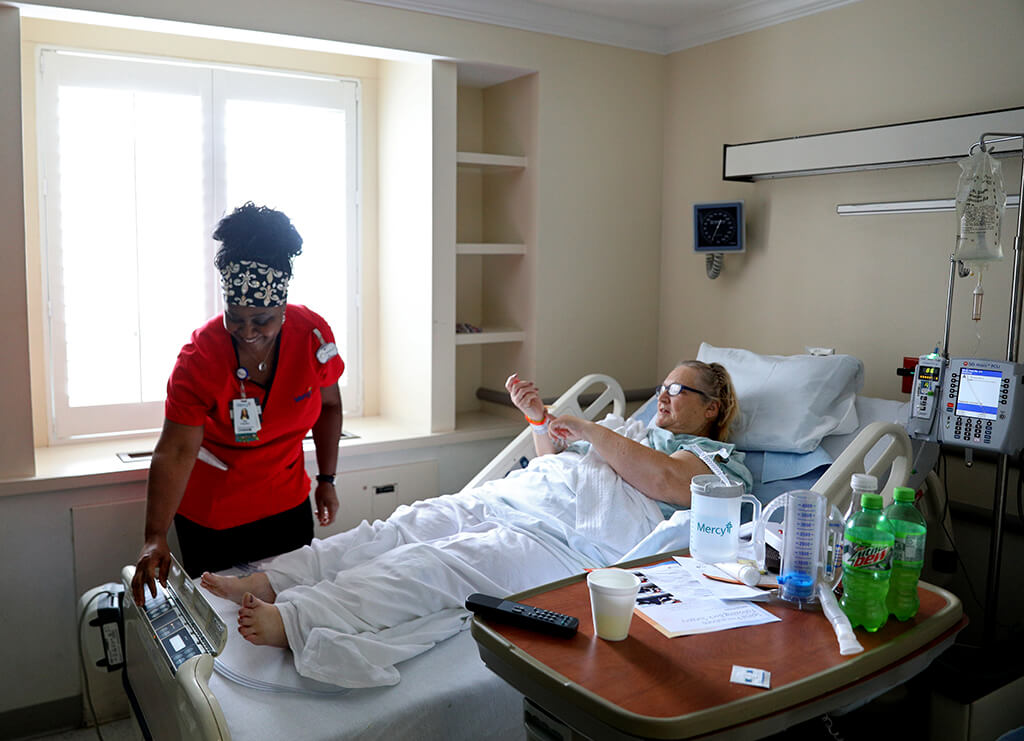 Lonni Schicker chats with her nurse D’juana “Dee” Franklin on Friday, Sept. 7, 2018, before getting a bed bath at Mercy Hospital St. Louis as she recovers from a recent back surgery there.