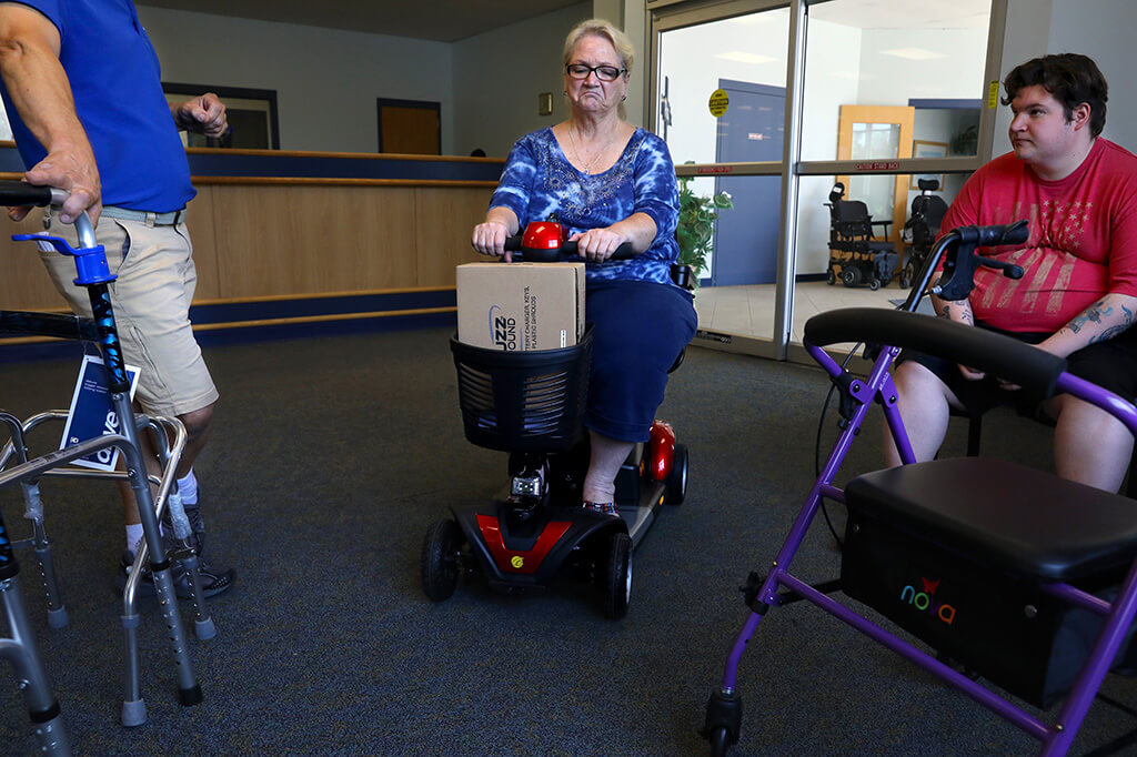 Lonni Schicker tries out a scooter with service technician Chris Puleo (left), as she shops with Dan at Provider Plus Inc. on Friday, August 3, 2018. The scooter could help her avoid falls, which have recently led to injuries.